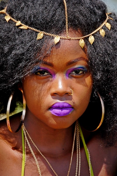 女人与黑色的头发戴着金色的鼻环,对循环耳环和紫色口红
